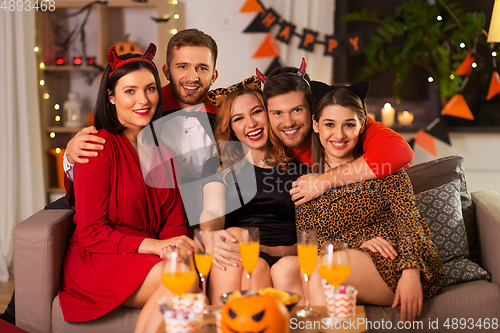 Image of happy friends in halloween costumes at home party