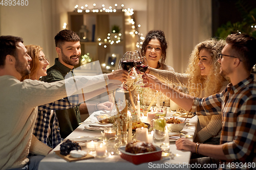 Image of happy friends drinking red wine at christmas party