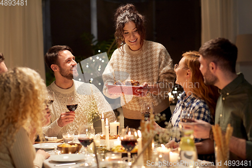 Image of happy friends having christmas dinner at home