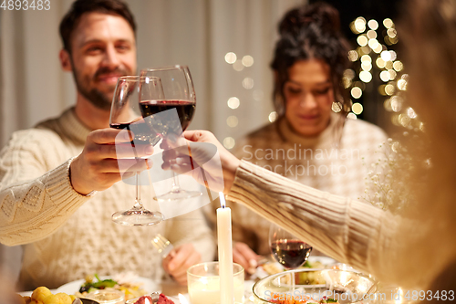 Image of happy friends drinking red wine at christmas party