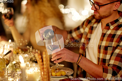 Image of man pouring red wine into glass at christmas party