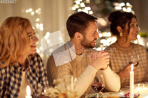 Image of happy friends having christmas dinner at home