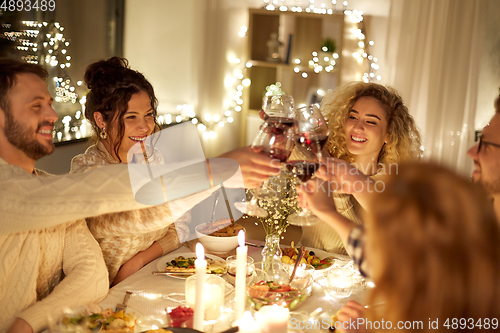 Image of happy friends drinking red wine at christmas party