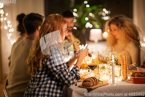 Image of woman with smartphone at dinner party with friends