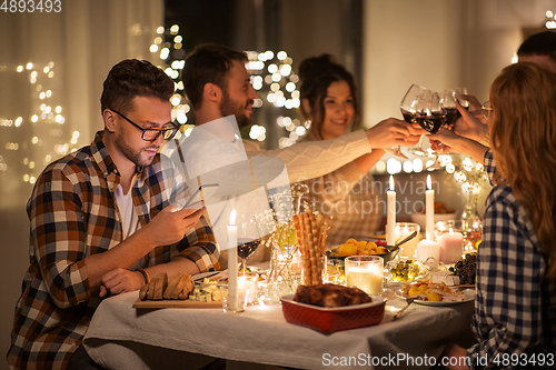 Image of man with smartphone at dinner party with friends