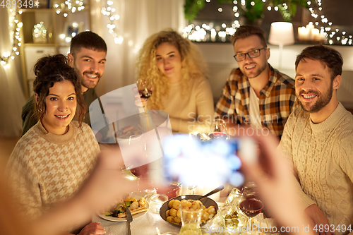 Image of friends photographing at christmas dinner party