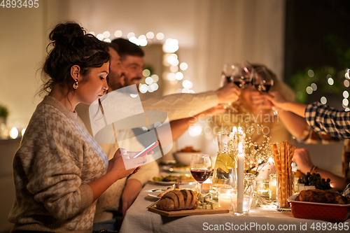 Image of woman with smartphone at dinner party with friends