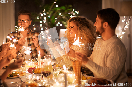 Image of happy friends having christmas dinner at home