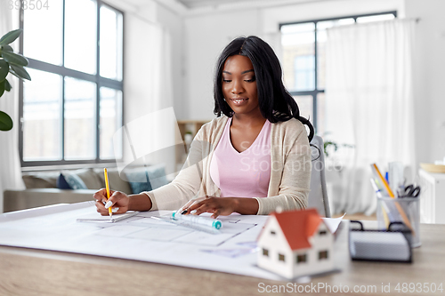 Image of female architect with house model and blueprint