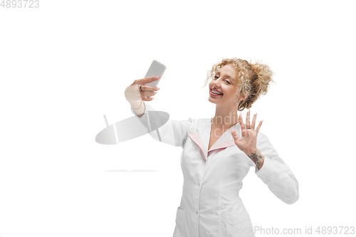 Image of Portrait of female doctor, nurse or cosmetologist in white uniform and blue gloves over white background