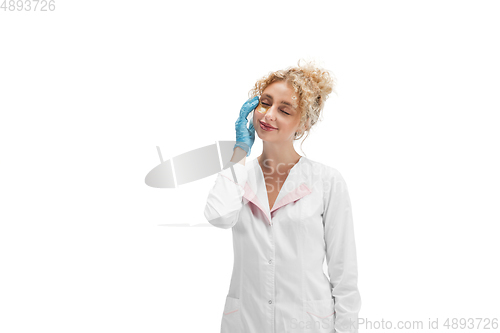 Image of Portrait of female doctor, nurse or cosmetologist in white uniform and blue gloves over white background