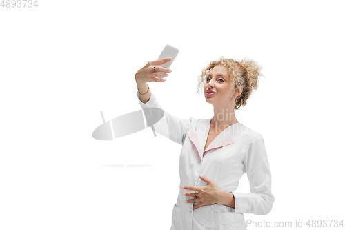 Image of Portrait of female doctor, nurse or cosmetologist in white uniform and blue gloves over white background