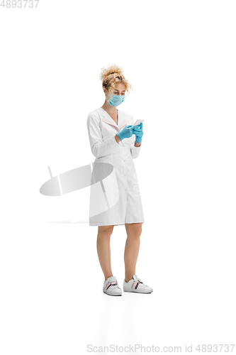 Image of Portrait of female doctor, nurse or cosmetologist in white uniform and blue gloves over white background