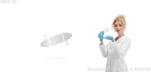 Image of Portrait of female doctor, nurse or cosmetologist in white uniform and blue gloves over white background
