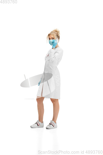 Image of Portrait of female doctor, nurse or cosmetologist in white uniform and blue gloves over white background