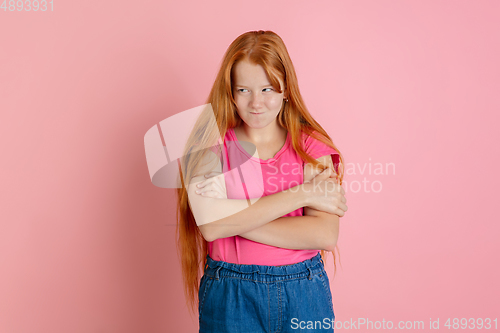 Image of Caucasian teen girl\'s portrait isolated on coral pink studio background.