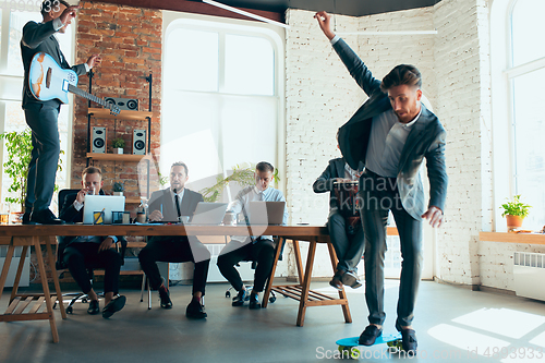 Image of Happy colleagues having fun in office while their colleagues working hard