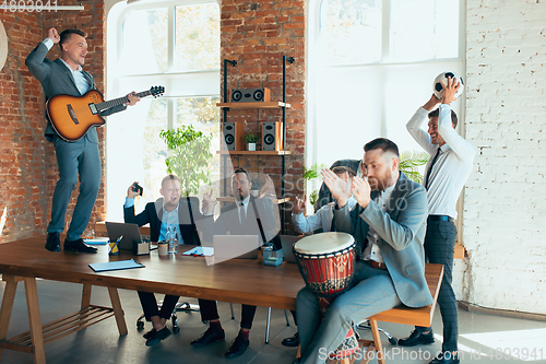 Image of Happy colleagues having fun in office while their colleagues working hard