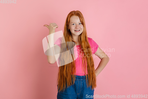 Image of Caucasian teen girl\'s portrait isolated on coral pink studio background.