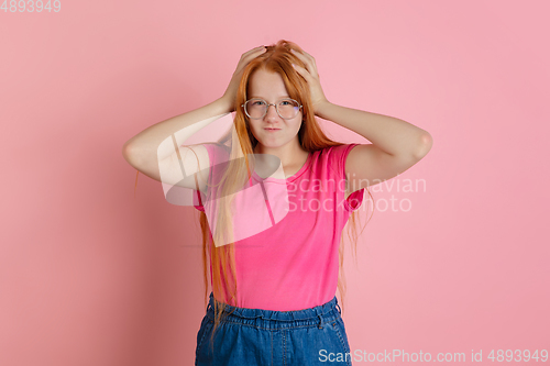 Image of Caucasian teen girl\'s portrait isolated on coral pink studio background.