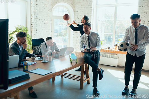 Image of Happy colleagues having fun in office while their colleagues working hard