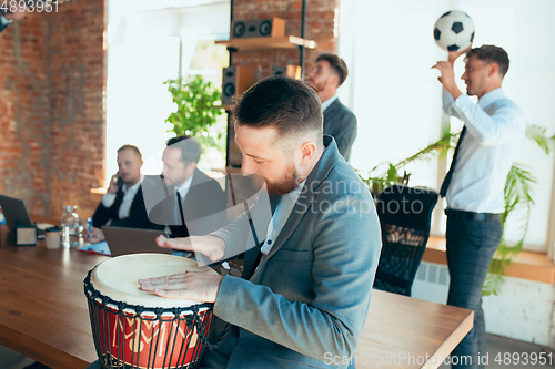 Image of Happy colleagues having fun in office while their colleagues working hard