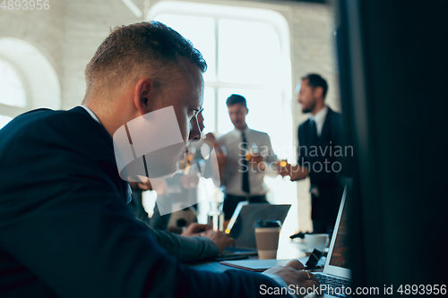 Image of Happy colleagues having fun in office while their colleagues working hard