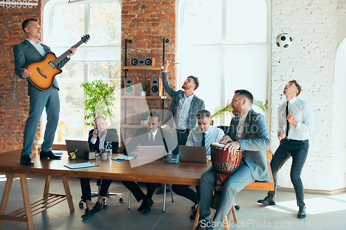 Image of Happy colleagues having fun in office while their colleagues working hard