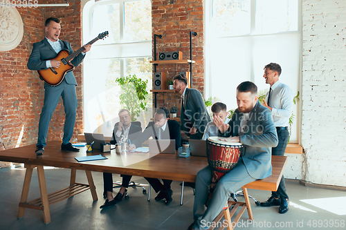 Image of Happy colleagues having fun in office while their colleagues working hard