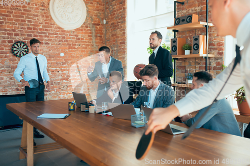 Image of Happy colleagues having fun in office while their colleagues working hard