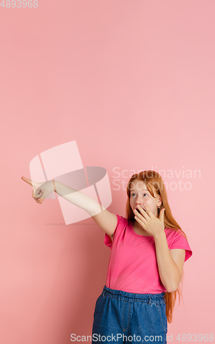 Image of Caucasian teen girl\'s portrait isolated on coral pink studio background.