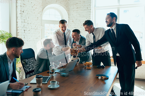 Image of Happy colleagues having fun in office while their colleagues working hard