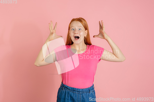 Image of Caucasian teen girl\'s portrait isolated on coral pink studio background.