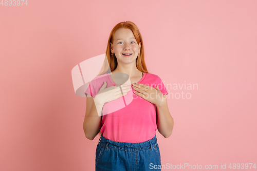 Image of Caucasian teen girl\'s portrait isolated on coral pink studio background.