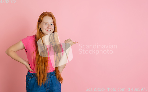 Image of Caucasian teen girl\'s portrait isolated on coral pink studio background.