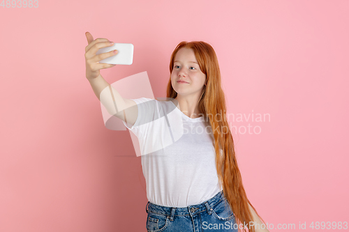 Image of Caucasian teen girl\'s portrait isolated on coral pink studio background.