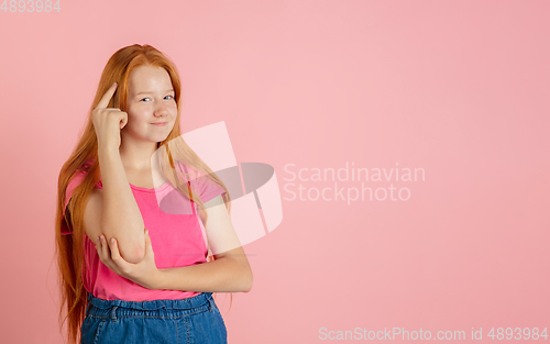 Image of Caucasian teen girl\'s portrait isolated on coral pink studio background.
