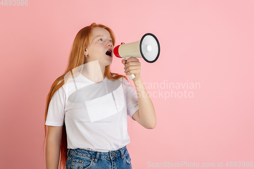 Image of Caucasian teen girl\'s portrait isolated on coral pink studio background.