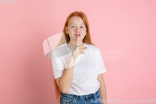 Image of Caucasian teen girl\'s portrait isolated on coral pink studio background.