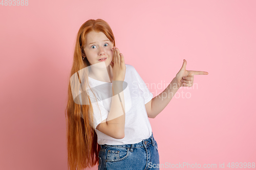 Image of Caucasian teen girl\'s portrait isolated on coral pink studio background.