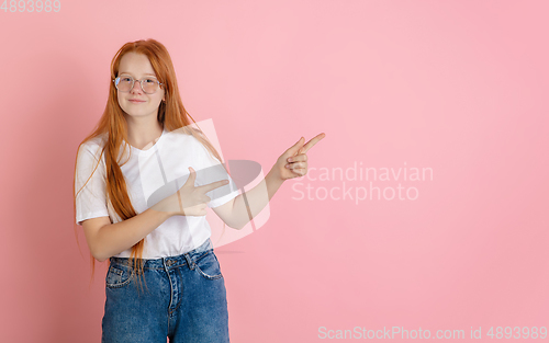 Image of Caucasian teen girl\'s portrait isolated on coral pink studio background.