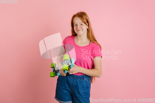 Image of Caucasian teen girl\'s portrait isolated on coral pink studio background.