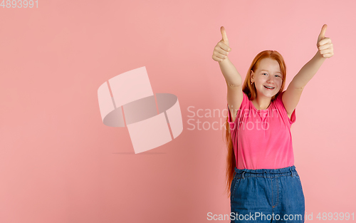 Image of Caucasian teen girl\'s portrait isolated on coral pink studio background.