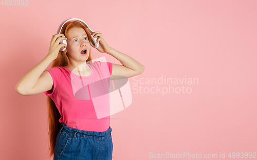 Image of Caucasian teen girl\'s portrait isolated on coral pink studio background.