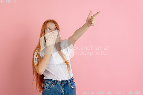 Image of Caucasian teen girl\'s portrait isolated on coral pink studio background.