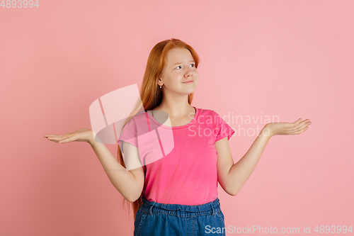 Image of Caucasian teen girl\'s portrait isolated on coral pink studio background.