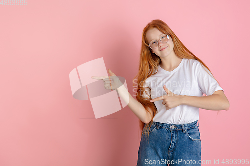 Image of Caucasian teen girl\'s portrait isolated on coral pink studio background.