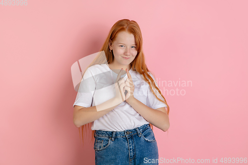 Image of Caucasian teen girl\'s portrait isolated on coral pink studio background.