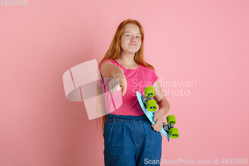 Image of Caucasian teen girl\'s portrait isolated on coral pink studio background.