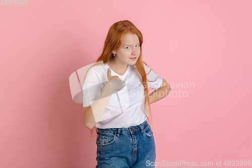 Image of Caucasian teen girl\'s portrait isolated on coral pink studio background.